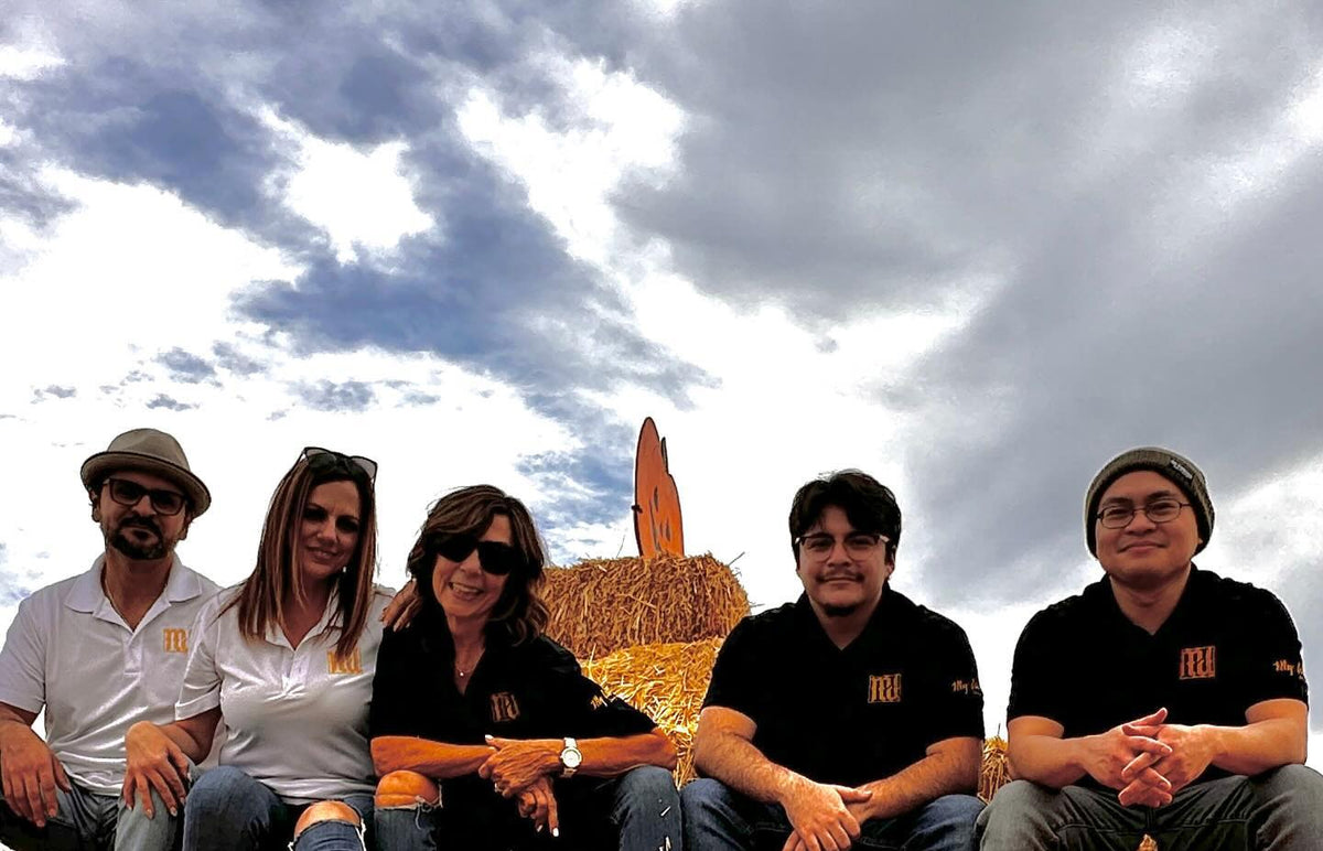 Five people outdoors wearing black and white polos with the MyCali Designs logo