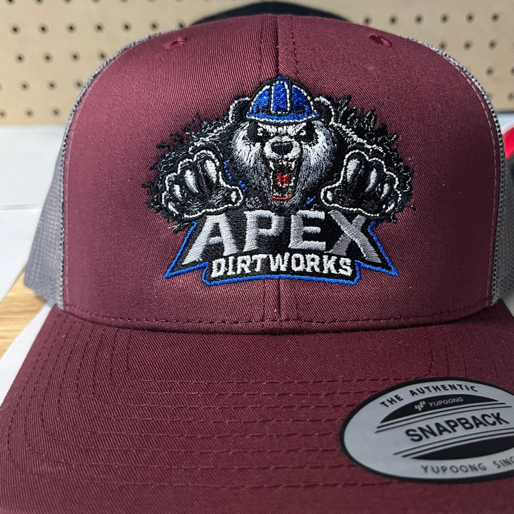 Embroidered excavation and dirt work company logo on a maroon and grey flat bill trucker snapback
