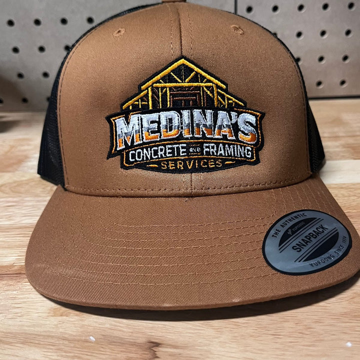 Embroidered concrete and framing contractor logo on a brown and black trucker snapback