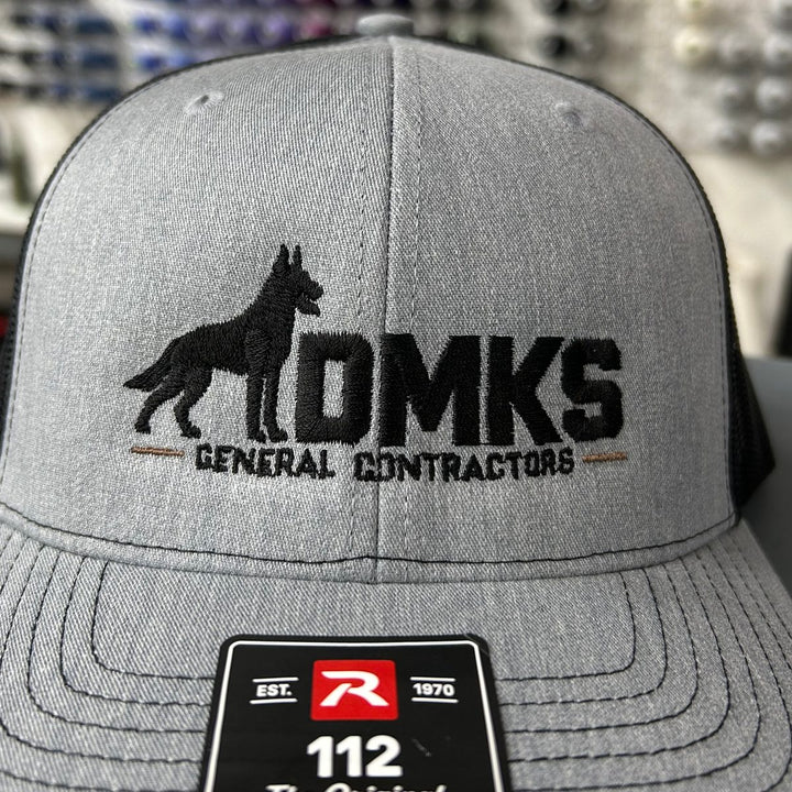 Embroidered general contractor logo on a heather grey and black Richardson 112 trucker hat