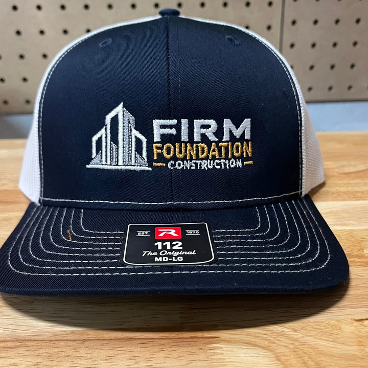 Embroidered construction company logo on a navy and white Richardson 112 trucker hat