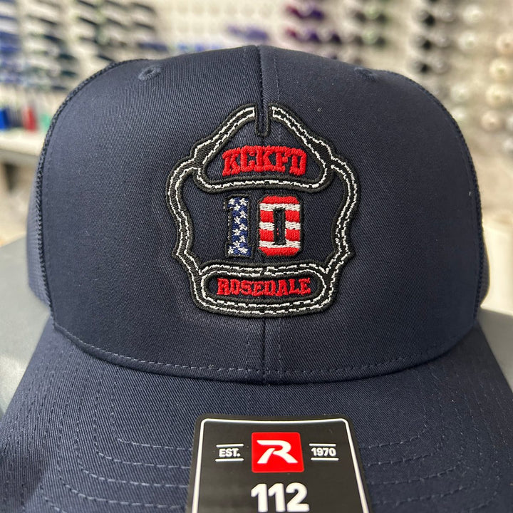 Embroidered fire department logo on a navy Richardson 112 trucker hat