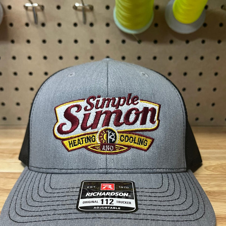 Embroidered heating and cooling company logo on a heather grey and black Richardson 112 trucker hat
