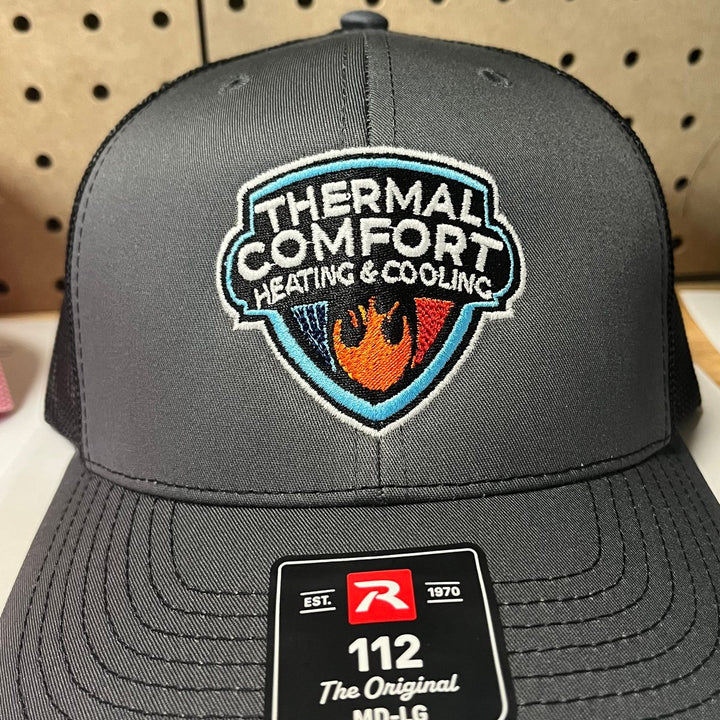 Embroidered heating and cooling company logo on a charcoal Richardson 112 trucker hat