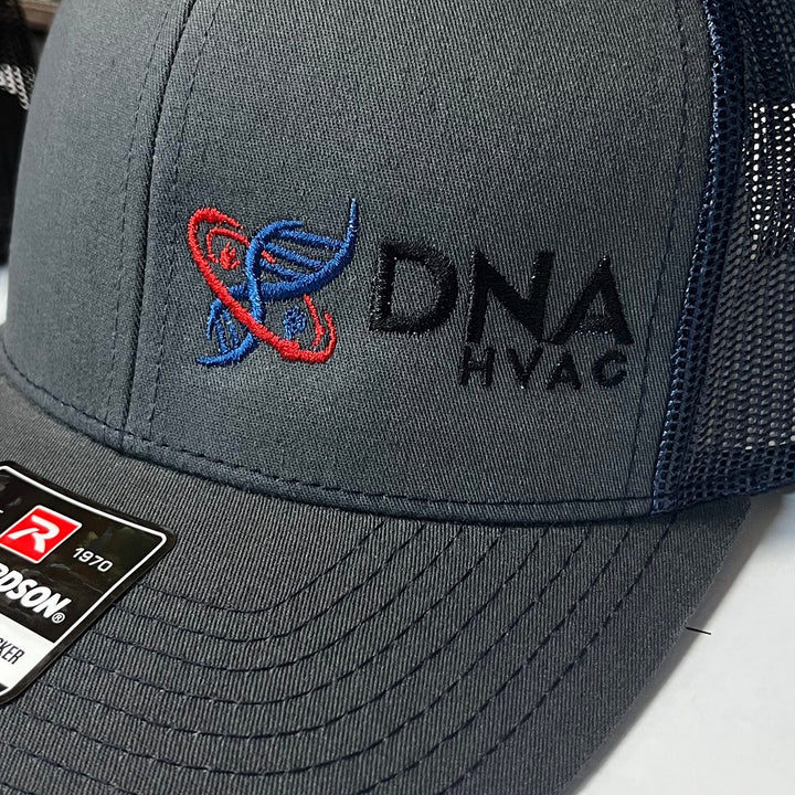 Embroidered HVAC company logo on a charcoal and navy Richardson 112 trucker hat