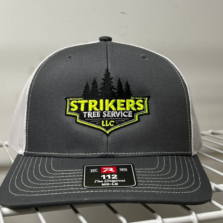Embroidered tree service logo on a charcoal and white Richardson 112 trucker hat
