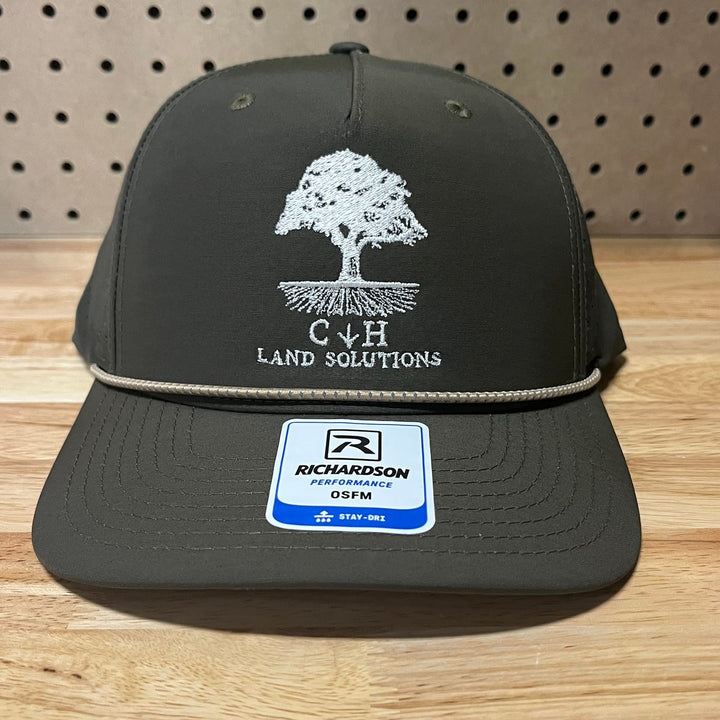 Embroidered land services company logo on a dark olive rope hat