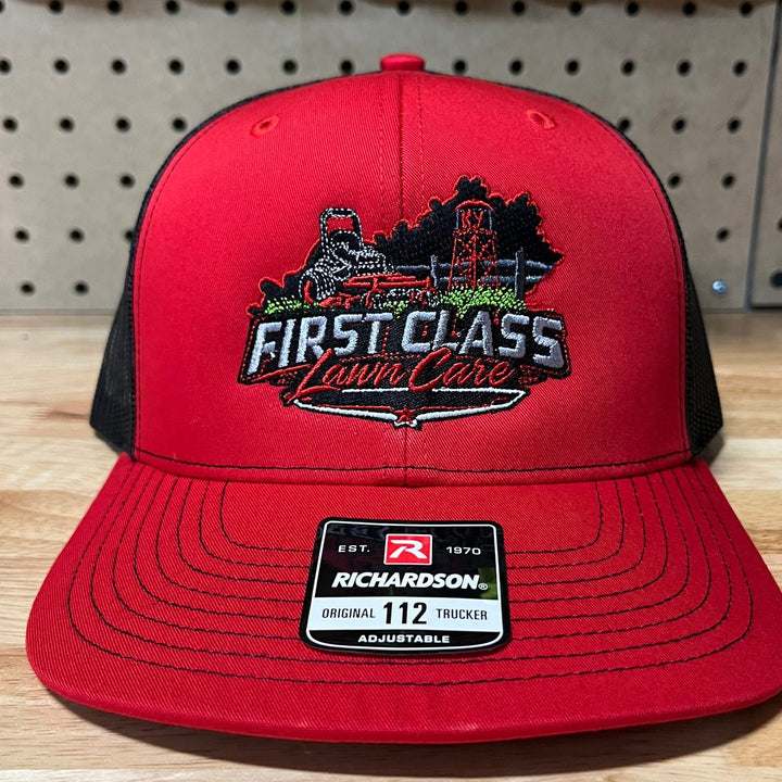 Embroidered lawn care company logo on a red and black Richardson 112 trucker hat