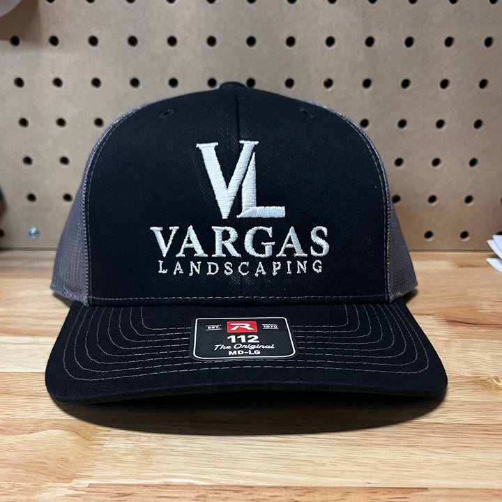 Embroidered landscaping company logo on a navy and charcoal Richardson 112 trucker hat