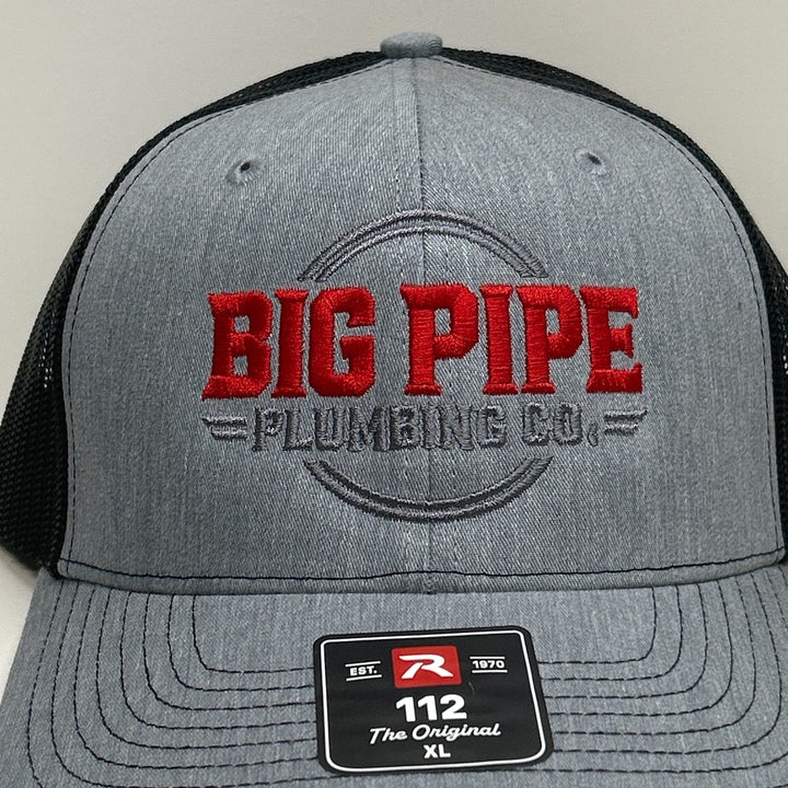 Embroidered plumbing company logo on a heather grey and black Richardson 112 trucker hat